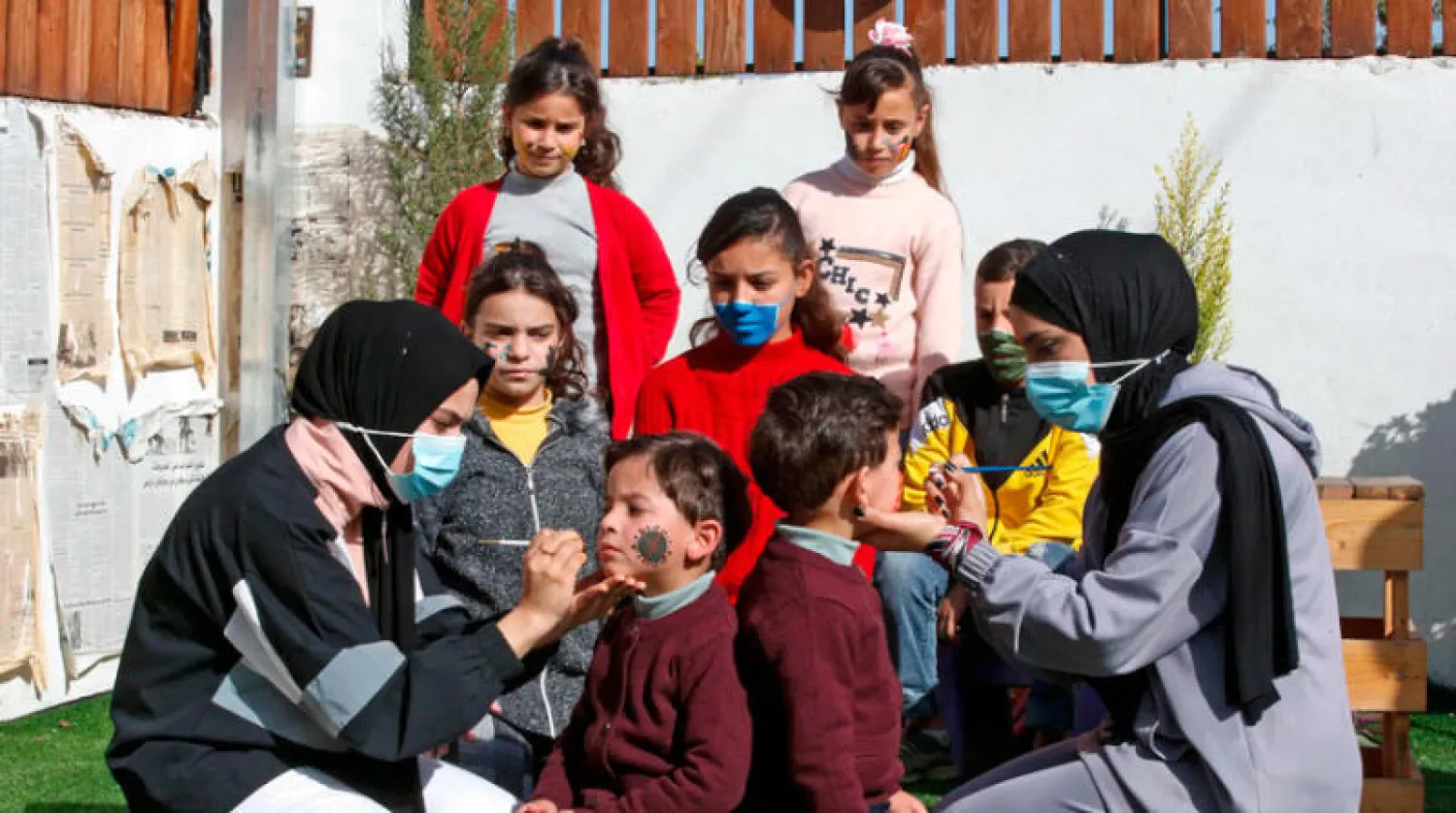 توعية الأطفال عبر رسم كمامات على وجوههم (أ.ف.ب)