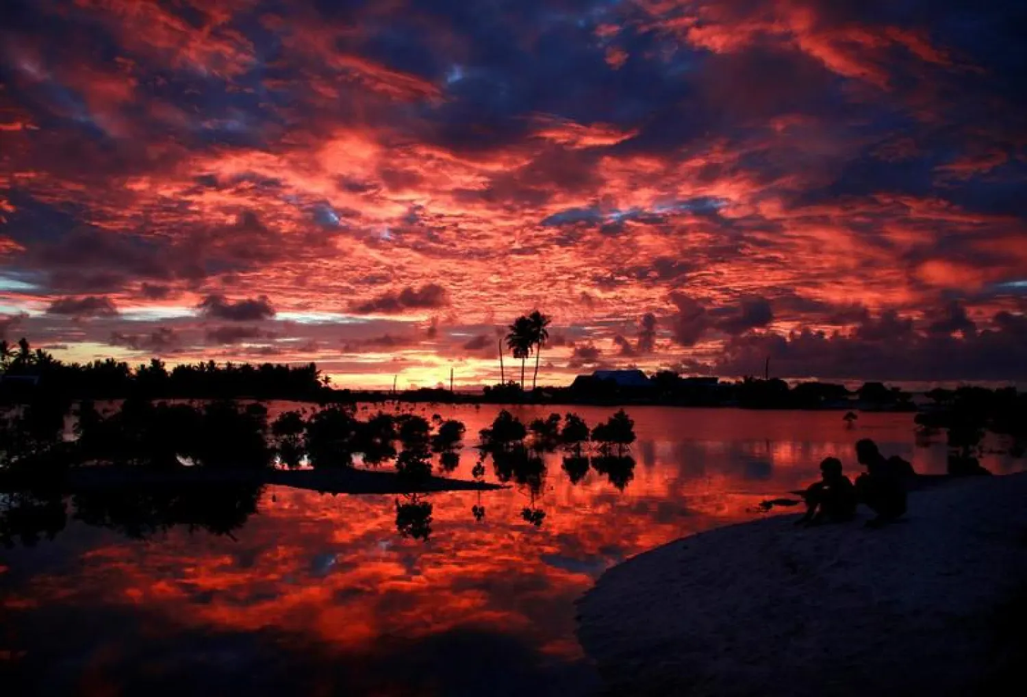 Villagers watch the sunset over a small lagoon near the village of Tangintebu on South Tarawa in the central Pacific Island nation of Kiribati | Photo: REUTERS
