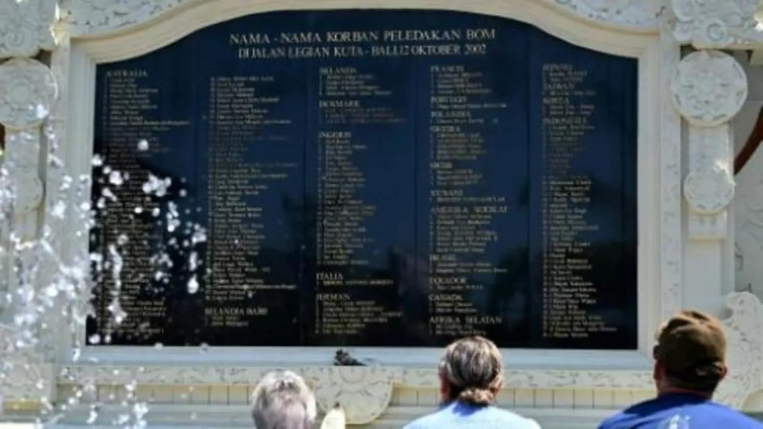 سياح أجانب أمام نصب تذكاري كُتبت عليه أسماء ضحايا اعتداءات بالي عام 2002 (أرشيفية - رويترز)
