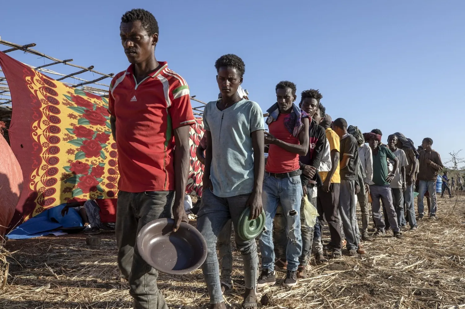 Tigrinyan refugees wait in line to receive cooked rice and lentils by Non Governmental Organization Muslim Aid, at Umm Rakouba refugee camp in Qadarif, eastern Sudan, Dec. 12, 2020. (AP)