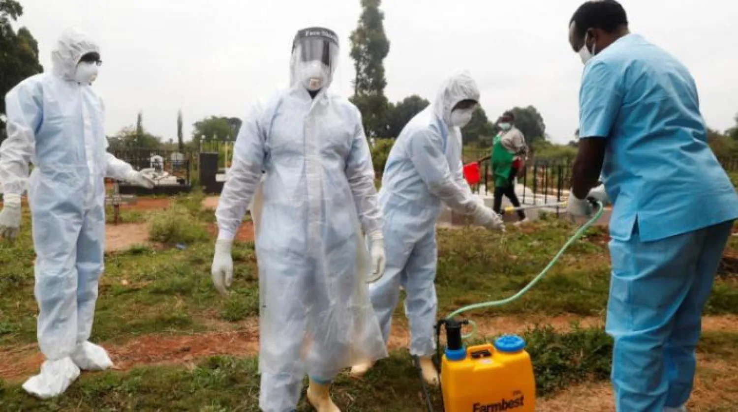 عاملون صحيون يعقمون ملابسهم ومعداتهم بعد دفن جثمان ضحية لـ«كورونا» في العاصمة الكينية نيروبي (رويترز)