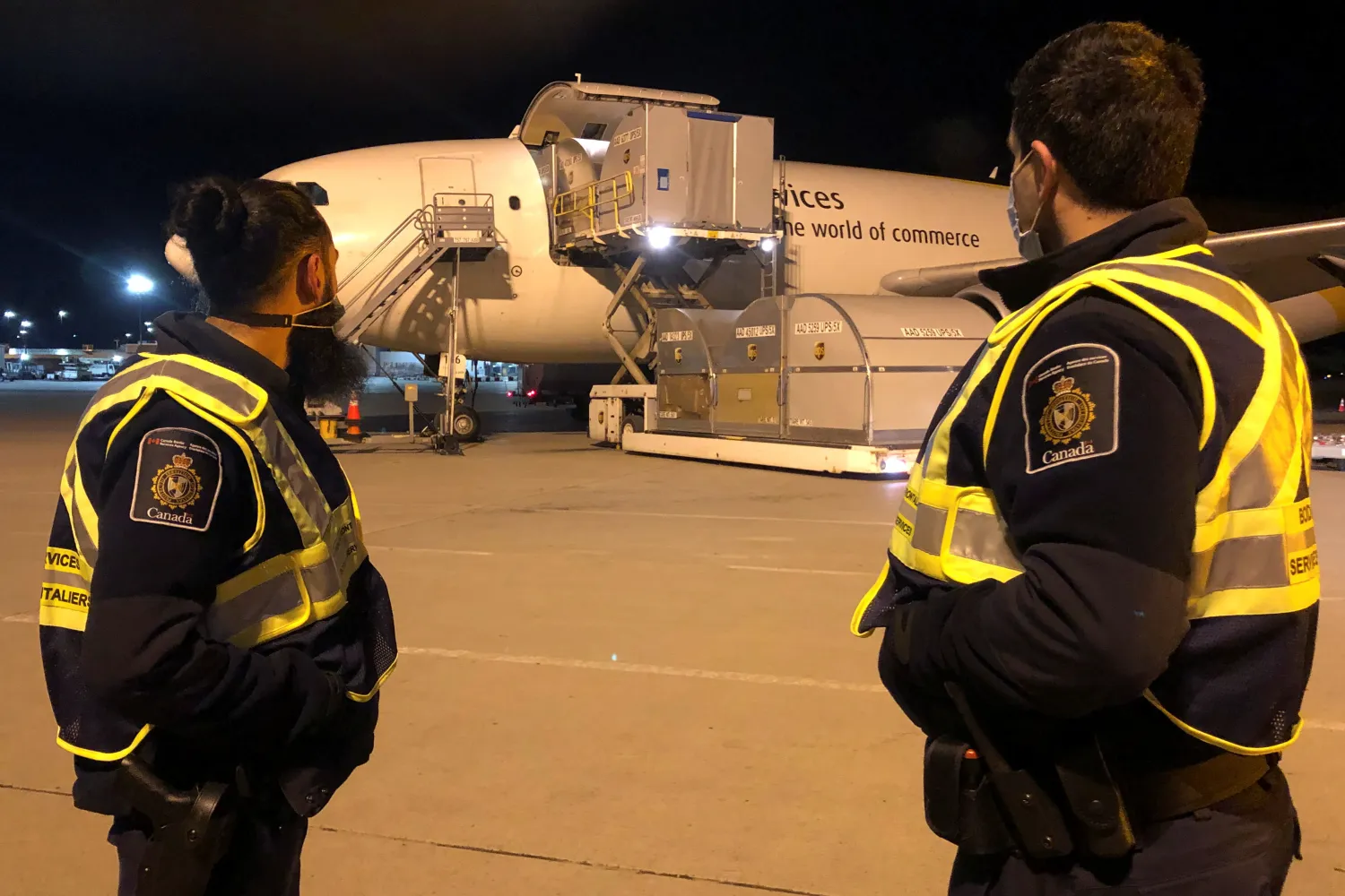 مسؤولو وكالة خدمات الحدود الكندية يشاهدون الدفعة الأولى من لقاحات «فايزر» تصل إلى مطار ميرابيل الدولي في مونتريال (رويترز)