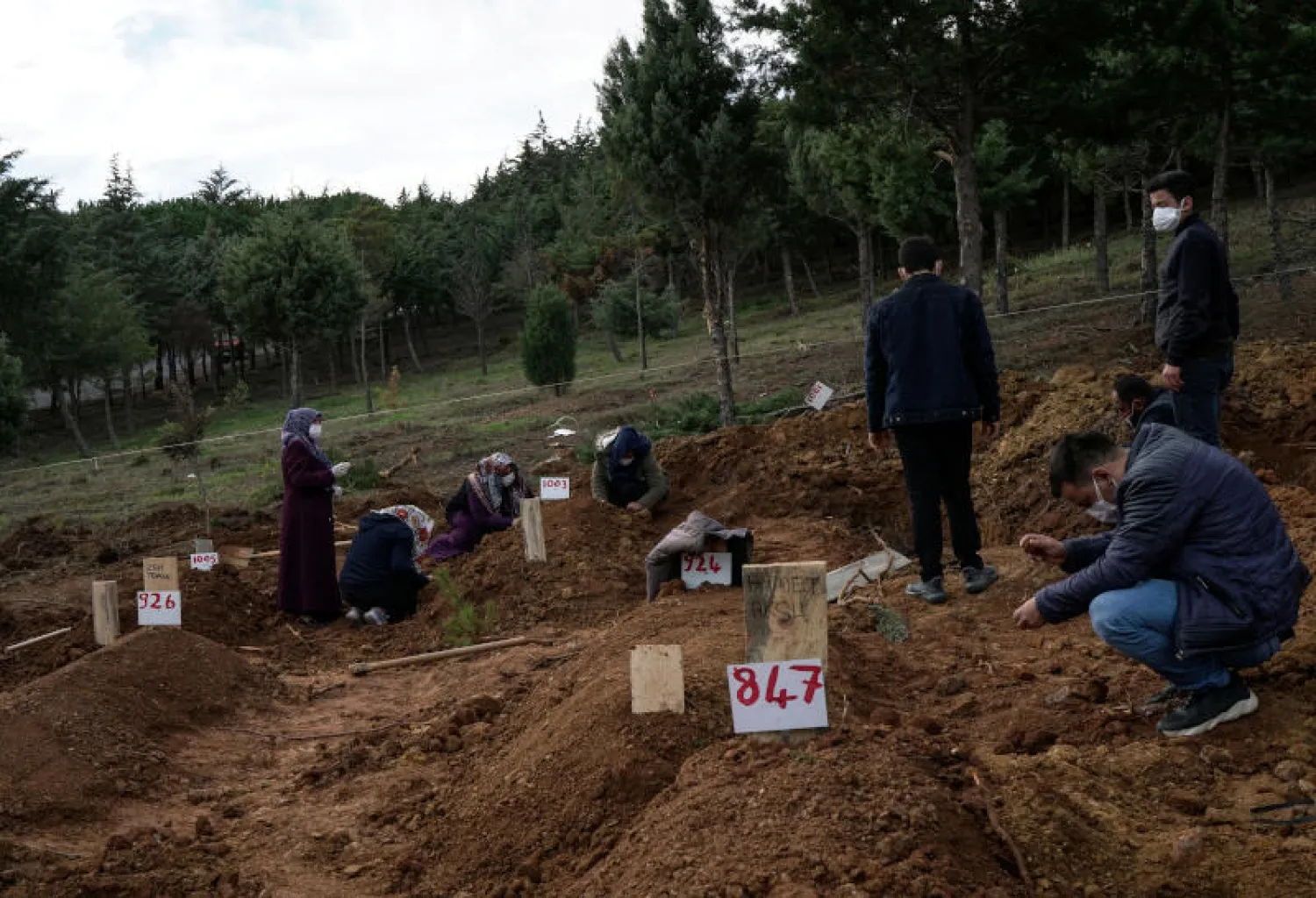 أشخاص يحضرون جنازة قريبهم ضحية وباء فيروس كورونا في مقبرة كيليوس في إسطنبول (رويترز)