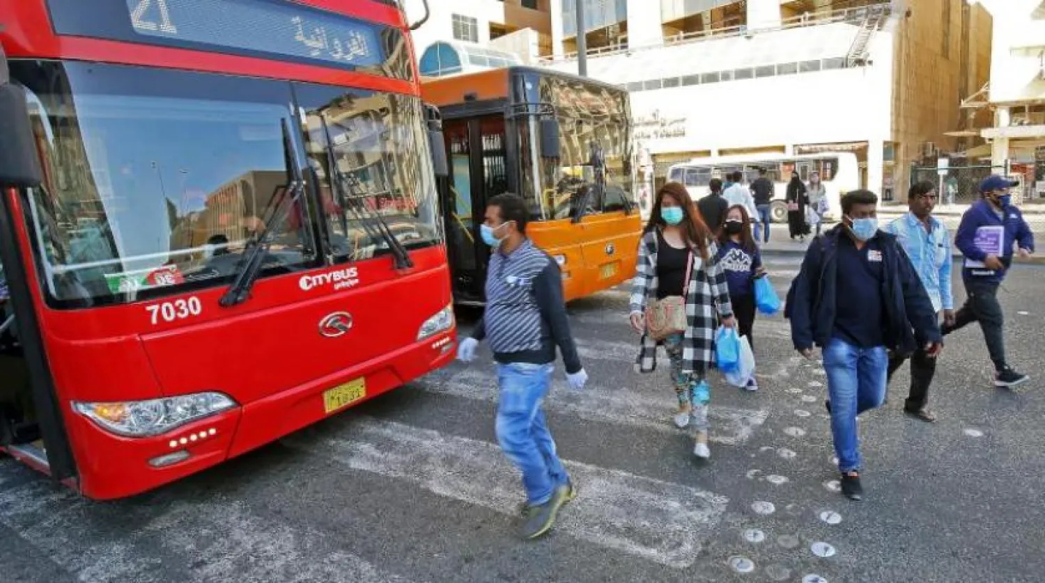 Başkent Kuveyt’te bir otobüs durağında koruyucu maske takan vatandaşlar (AFP)