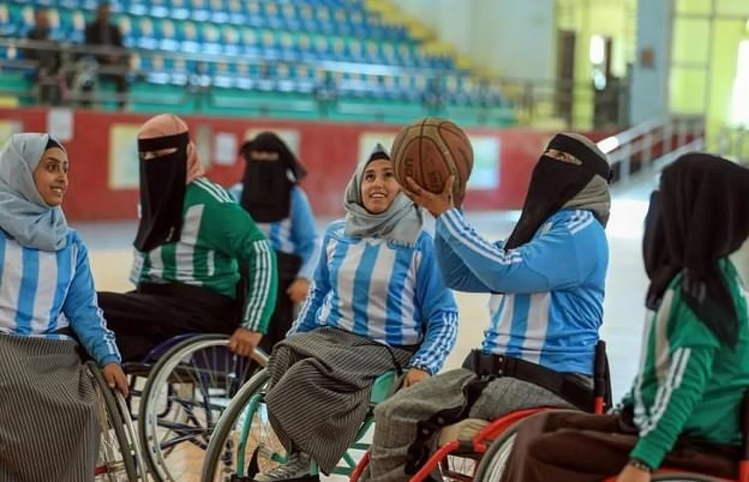 The female players, some wearing face coverings as well as their headscarves, jostled and shot baskets from sports wheelchairs painted red and light-green at the indoor court - AFP
 -