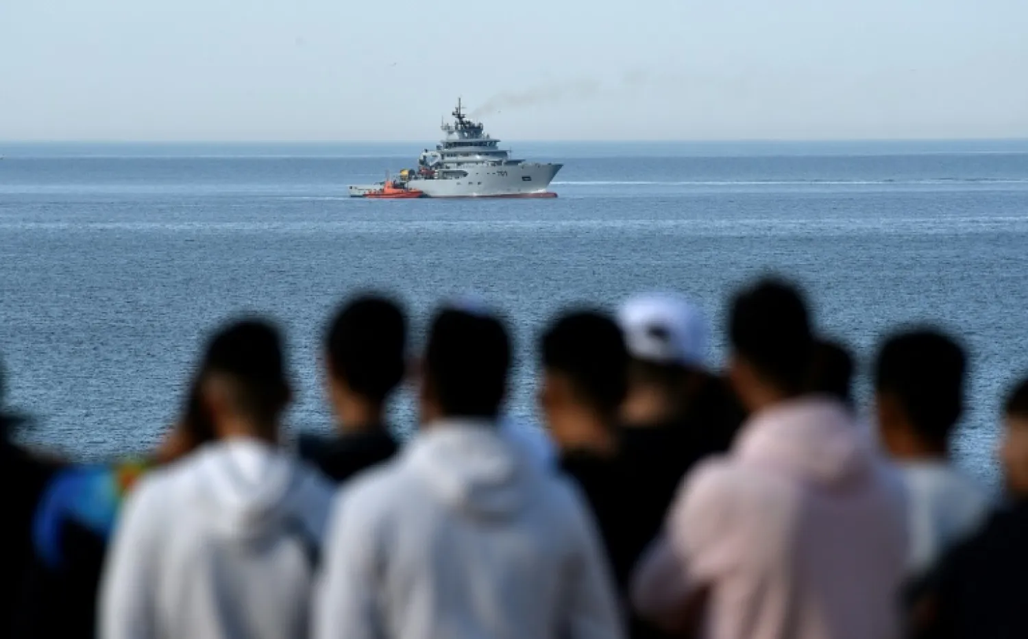 People watch as a naval ship arrives at the scene of a helicopter crash in the Mediterranean Sea off the coast of Algeria on Wednesday. (AFP)