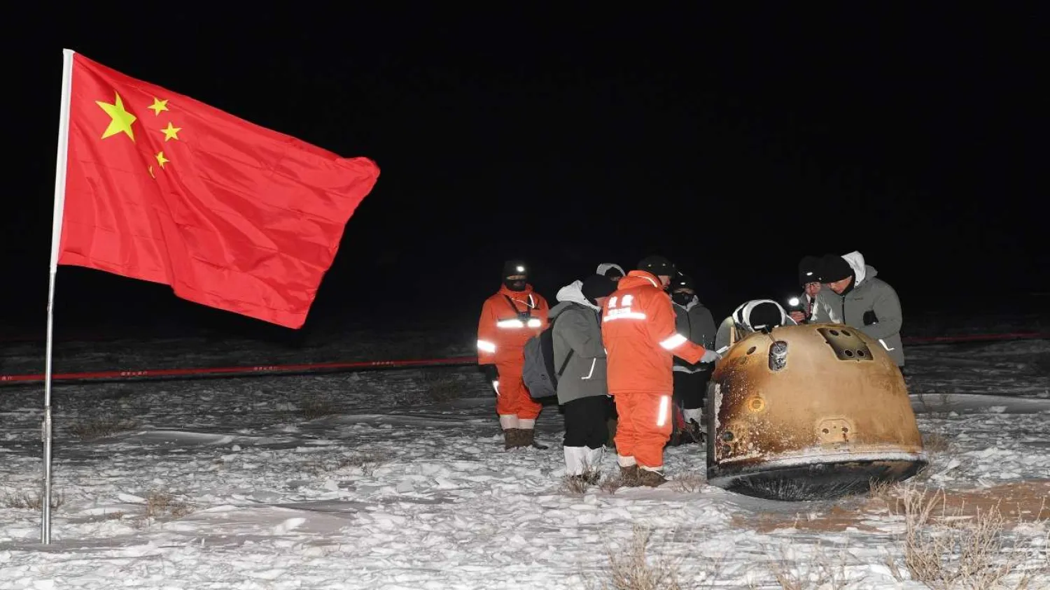 Researchers work around Chang'e-5 lunar return capsule carrying moon samples next to a Chinese national flag, after it landed in northern China's Inner Mongolia Autonomous Region, December 17, 2020. China Daily via REUTERS