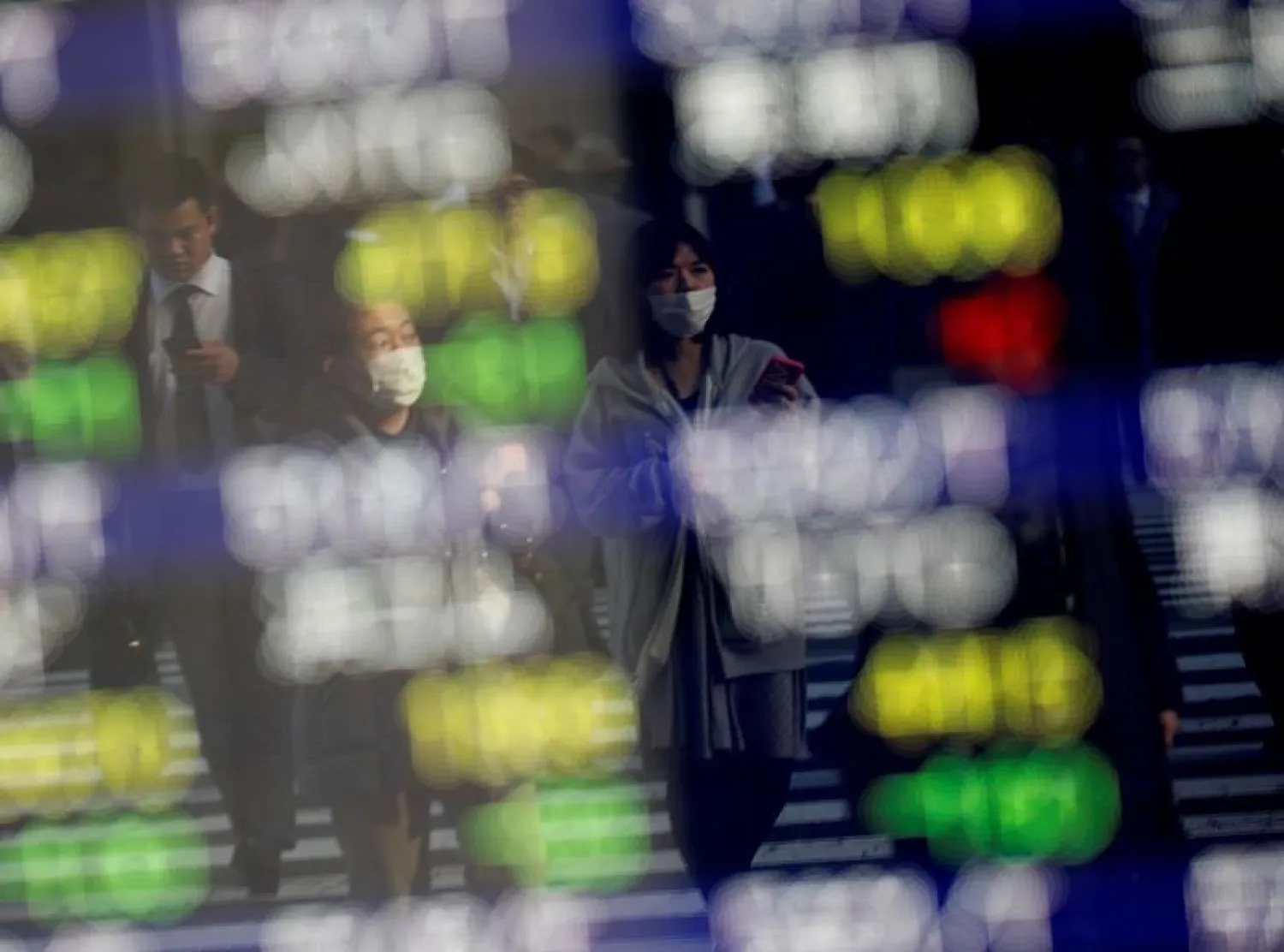 Pedestrians wearing facial masks are reflected on an electric board showing stock prices outside a brokerage at a business district in Tokyo, Japan January 30, 2020. REUTERS/Kim Kyung-Hoon