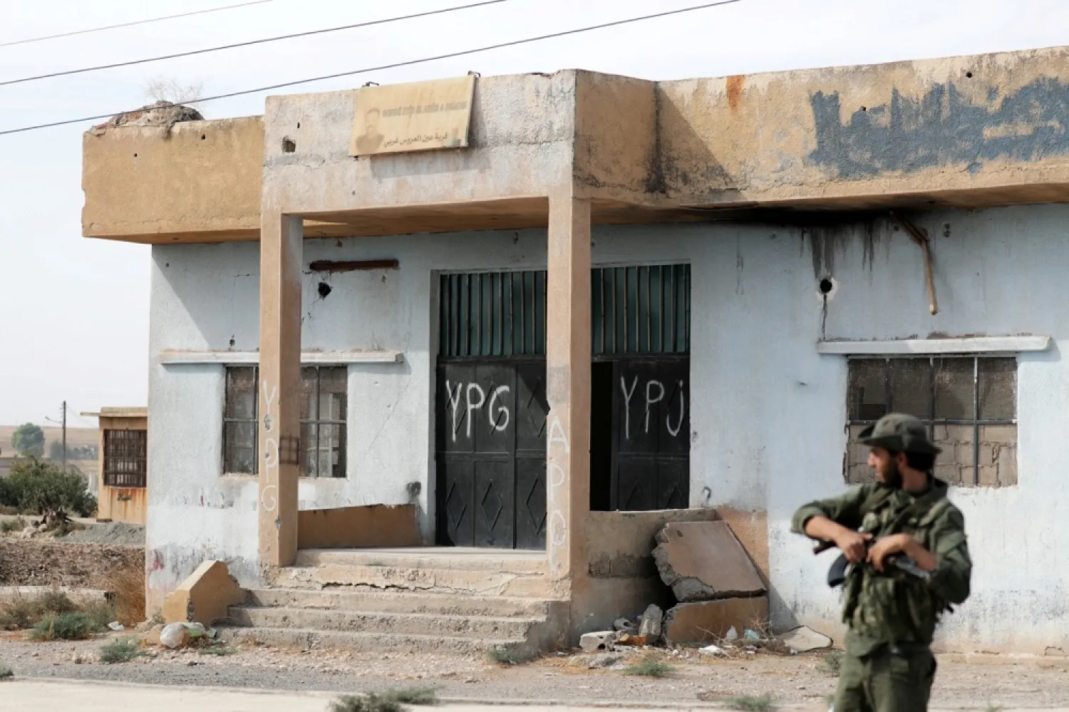 A Turkey-backed Syrian opposition fighter stands near a former YPG office at the entrance of Tel Abyad, Syria, October 14, 2019. (Reuters)