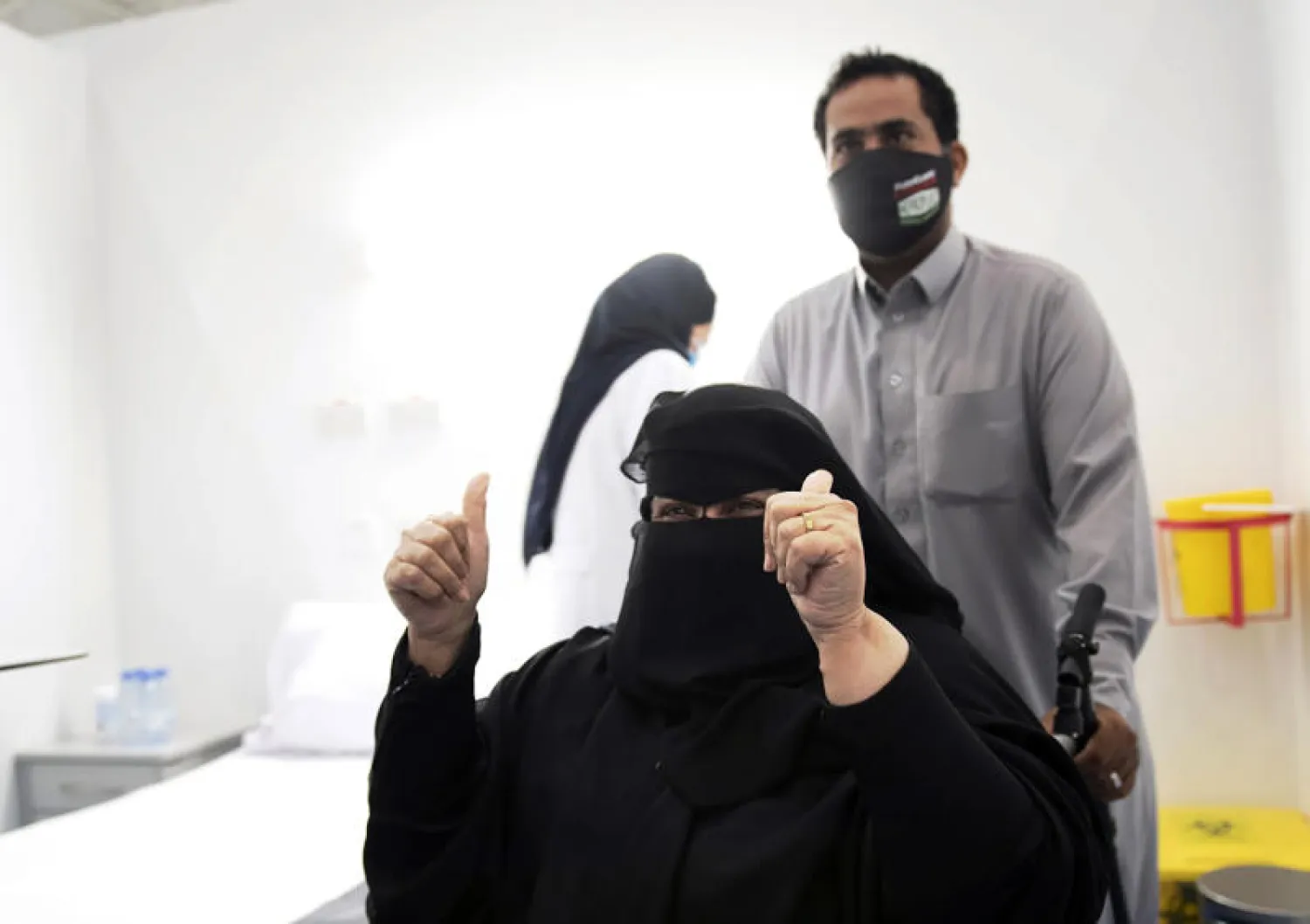 سيدة سعودية ترفع إبهامها بعد أن تلقت أحد أولى تطعيمات اللقاح في الرياض (أ.ب)