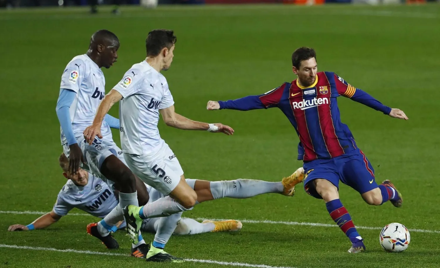 Barcelona's Lionel Messi, right, takes a shot at goal during the La Liga match between Barcelona and Valencia at the Camp Nou stadium in Barcelona, Spain, Dec. 19, 2020. (AP)