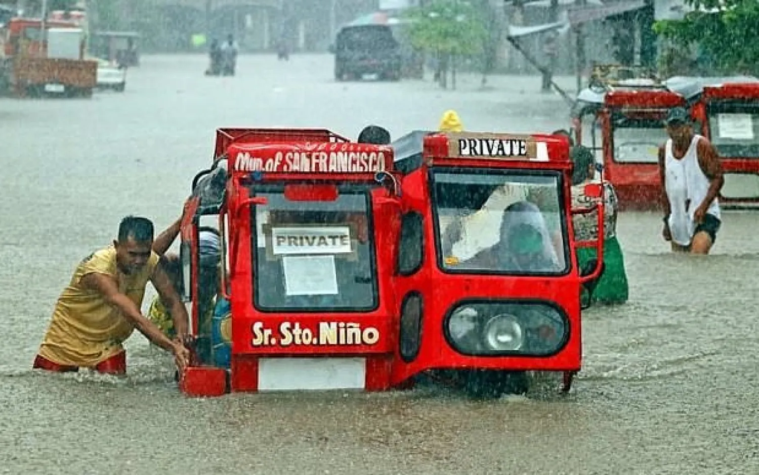 People push a half-submerged tricycle through a flooded street in Agusan del Sur province in Mindanao - AFP
 
