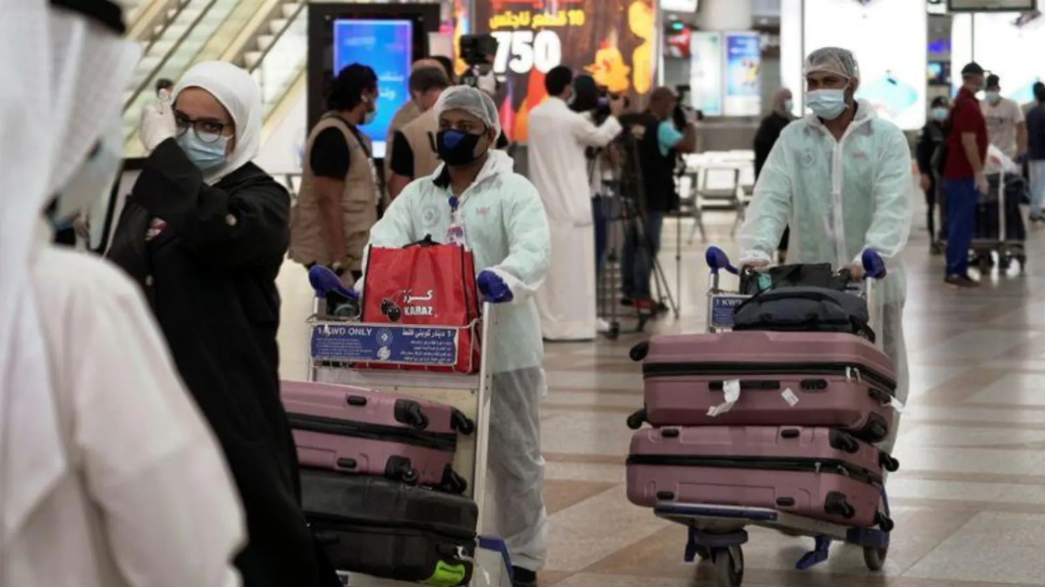 Repatriated Kuwaitis from Amman, Jordan, wearing protective face masks and suits, are seen after arriving at the Kuwait Airport, Kuwait City, Kuwait April 21, 2020. /Reuters