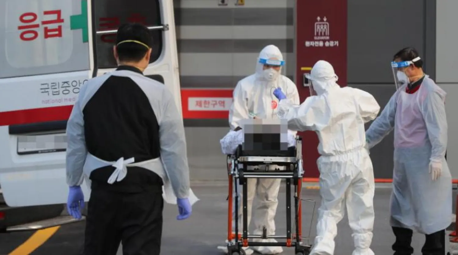 Koruyucu giysiler giyen doktorlar, koronavirüs hastalığı olan bir hastayı ambulansla Seul Ulusal Tıp Merkezi'ne sevk ediyor.  (EPA) 
