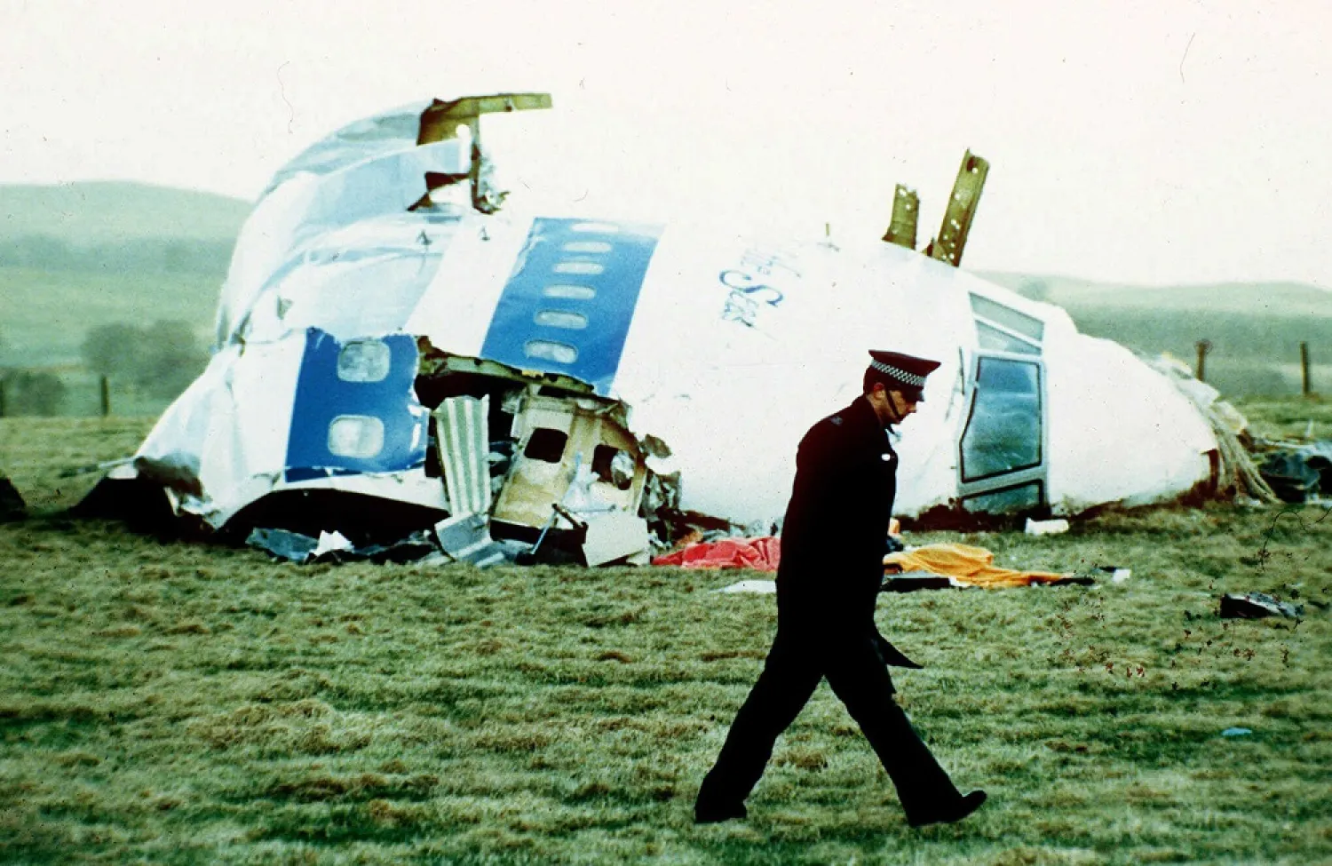 A police officer walks by the nose of Pan Am flight 103 in a field near the town of Lockerbie, Scotland where it lay after a bomb aboard exploded on Dec. 21, 1988. (AP)