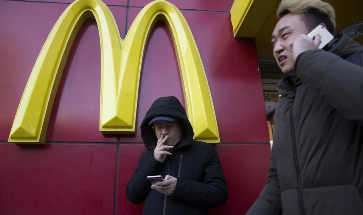 In this Jan. 10, 2017, file photo, a man smokes outside a McDonald's restaurant in Beijing, China. McDonald's is selling a sandwich made of Spam topped with crushed Oreo cookies Monday, Dec. 21, 2020 in China in an attention-grabbing move that has raised eyebrows. (AP Photo/Ng Han Guan, File)
