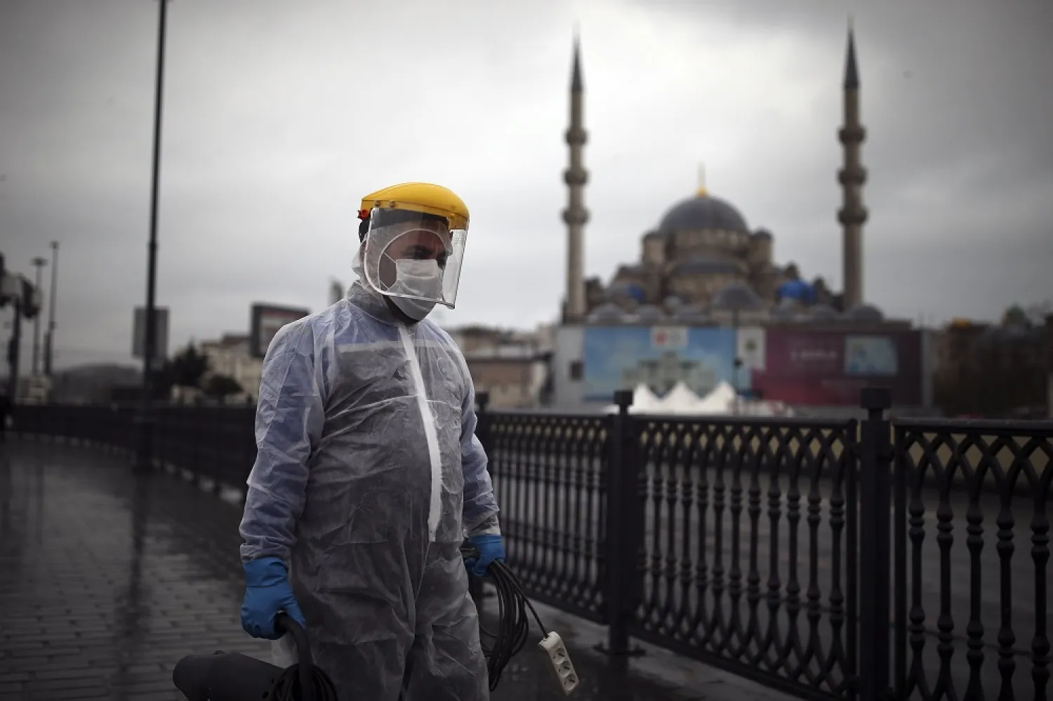A municipality worker wearing a protective suit to help curb the spread of the coronavirus, walks to spray disinfectant on Galata Bridge over the Golden Horn in Istanbul, Turkey, Dec. 15, 2020. (AP)