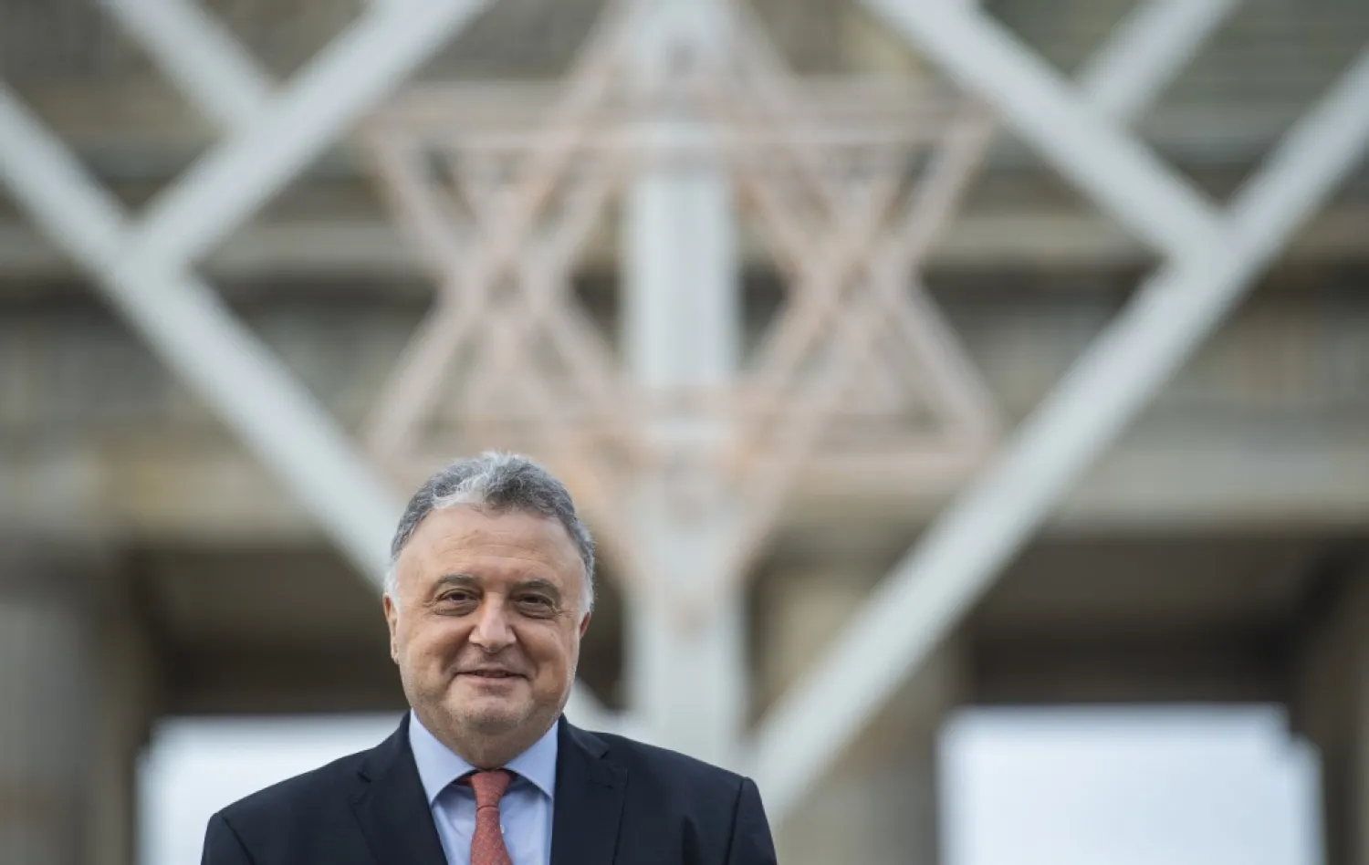 Jeremy Issacharoff, the Israeli ambassador to Berlin, poses in front of a giant Menora set up for the Jewish Hanukka Festival of Lights in front of Berlin's Brandenburg Gate, prior to an interview with AFP on December 17, 2020. (John MACDOUGALL/AFP)