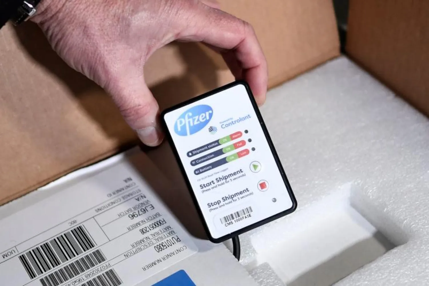 عامل يحمل نظام التحكم السلكي الذي يسمح بالتحقق مما إذا كانت سلسلة التبريد لم تنقطع عند وصول الشحنة الأولى من اللقاحات (أ.ف.ب)