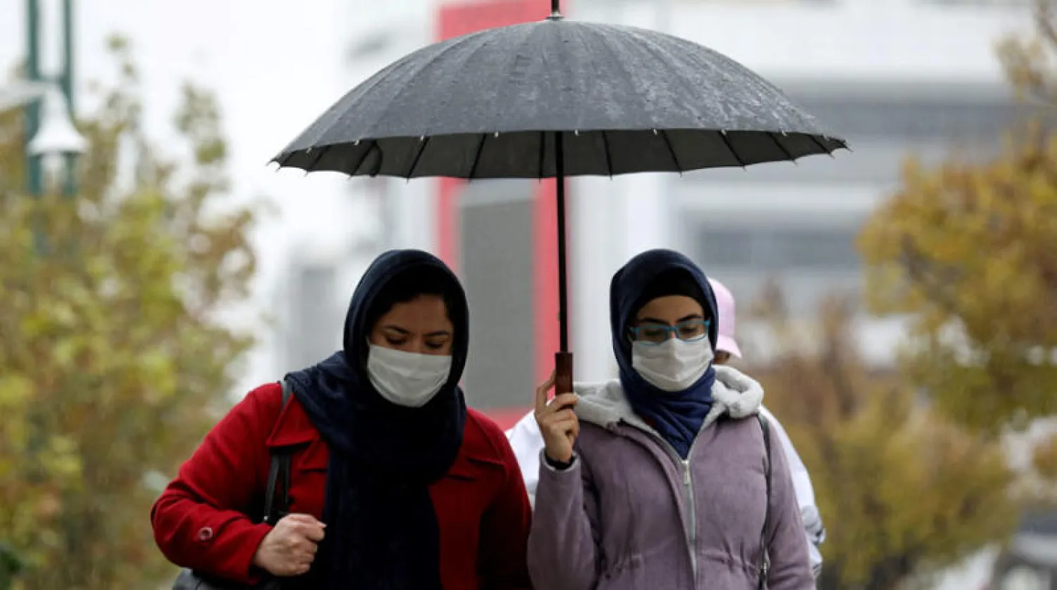 إيرانيتان تسيران في الشارع أثناء هطول أمطار في طهران أول من أمس (رويترز)