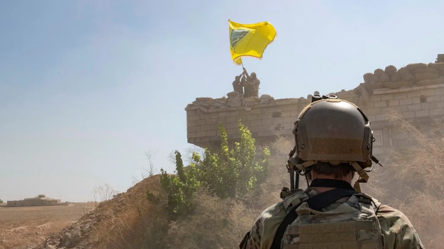 A US soldier oversees members of the Syrian Democratic Forces as they raise a Tal Abyad Military Council flag. (Reuters)