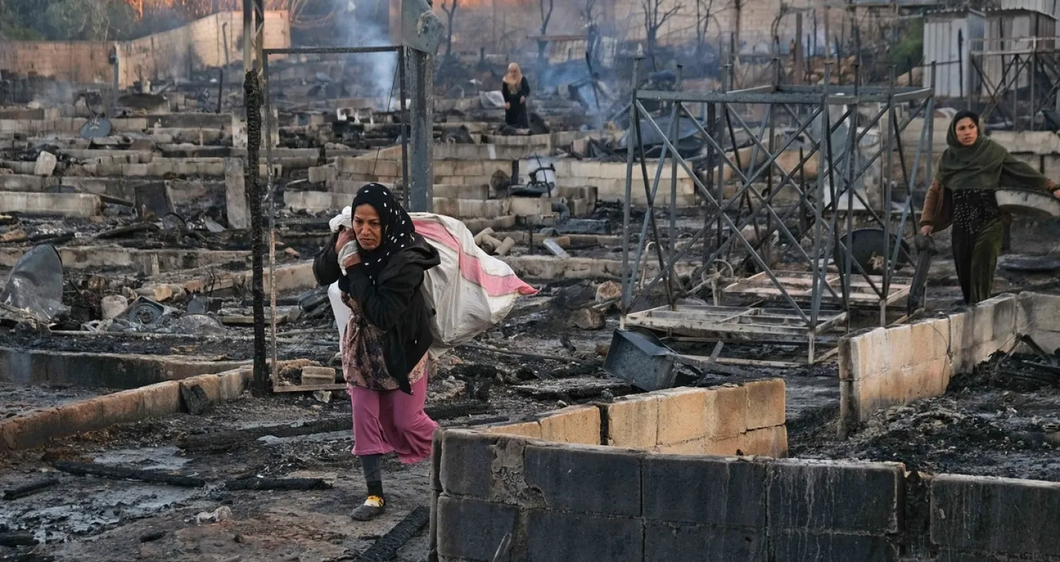 Syrian refugees salvage belongings from the wreckage of their shelters at a camp set on fire overnight in the northern Lebanese town of Bhanine on December 27, 2020, following a fight between members of the camp and a local Lebanese family. (Photo by Ibrahim CHALHOUB / AFP)