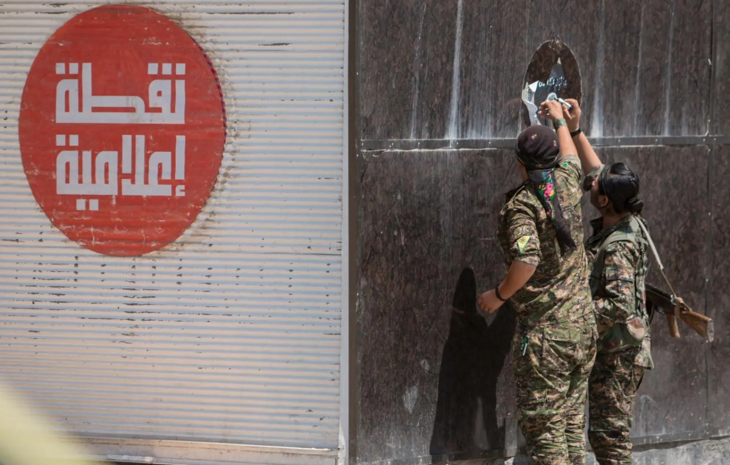 Kurdish People's Protection Units (YPG) fighters remove an ISIS sticker in Tel Abyad town, Raqqa governorate, June 16, 2015. REUTERS/Rodi Said