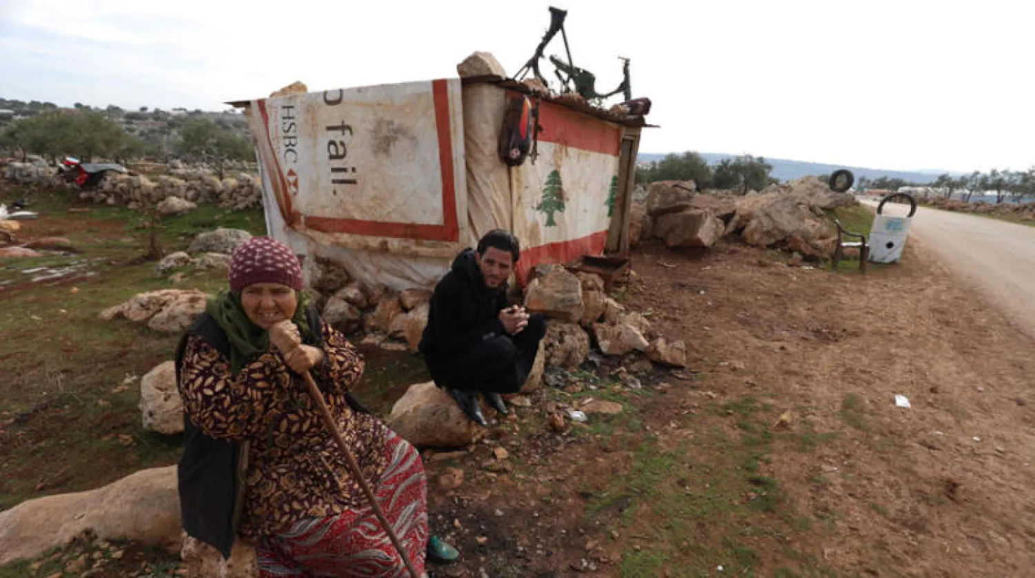 نازح سوري أمام محل لتصليح إطارات السيارات زيّنه بعلم لبنان في ريف إدلب تضامناً مع اللبنانيين بعد الانفجار الضخم في مرفأ بيروت الصيف الماضي  (أ.ف.ب)