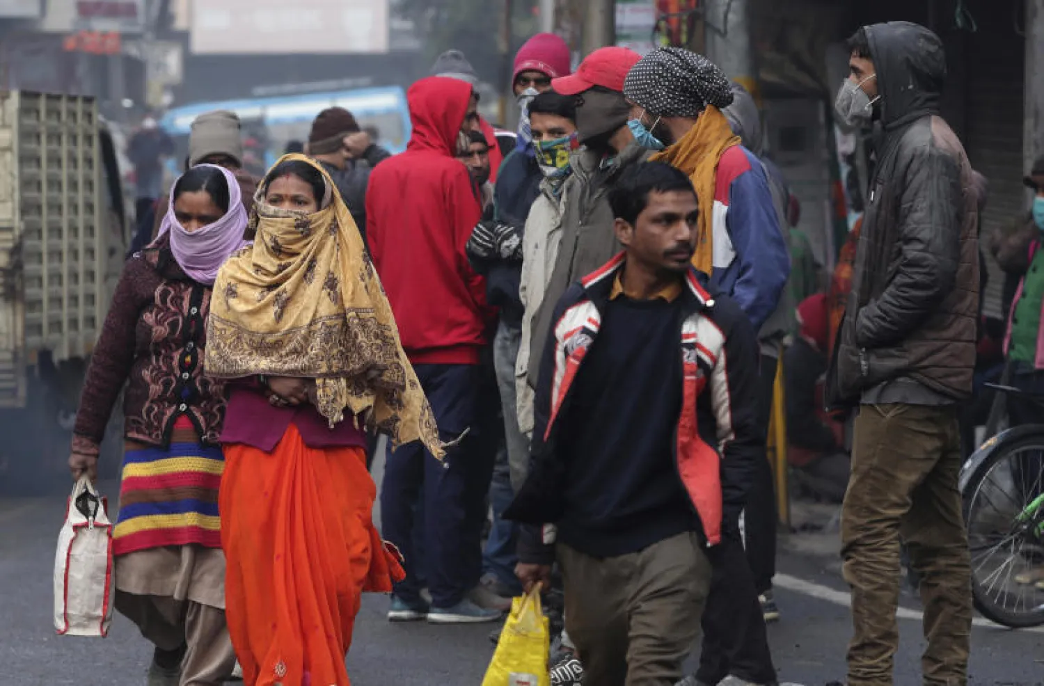 عمال ونساء يرتدون أقنعة واقية في جامو بالهند (أ.ب)