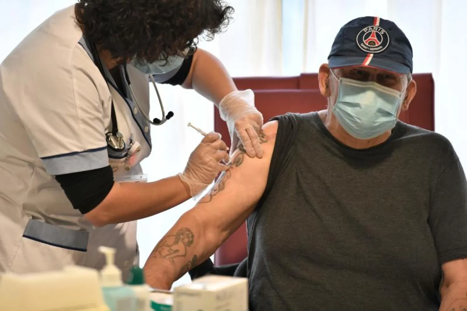 ممرضة تحقن رجل في إحدي دور رعاية المسنين في فرنسا بلقاح «فايزر» المضاد لفيروس «كورونا» (أ.ف.ب)