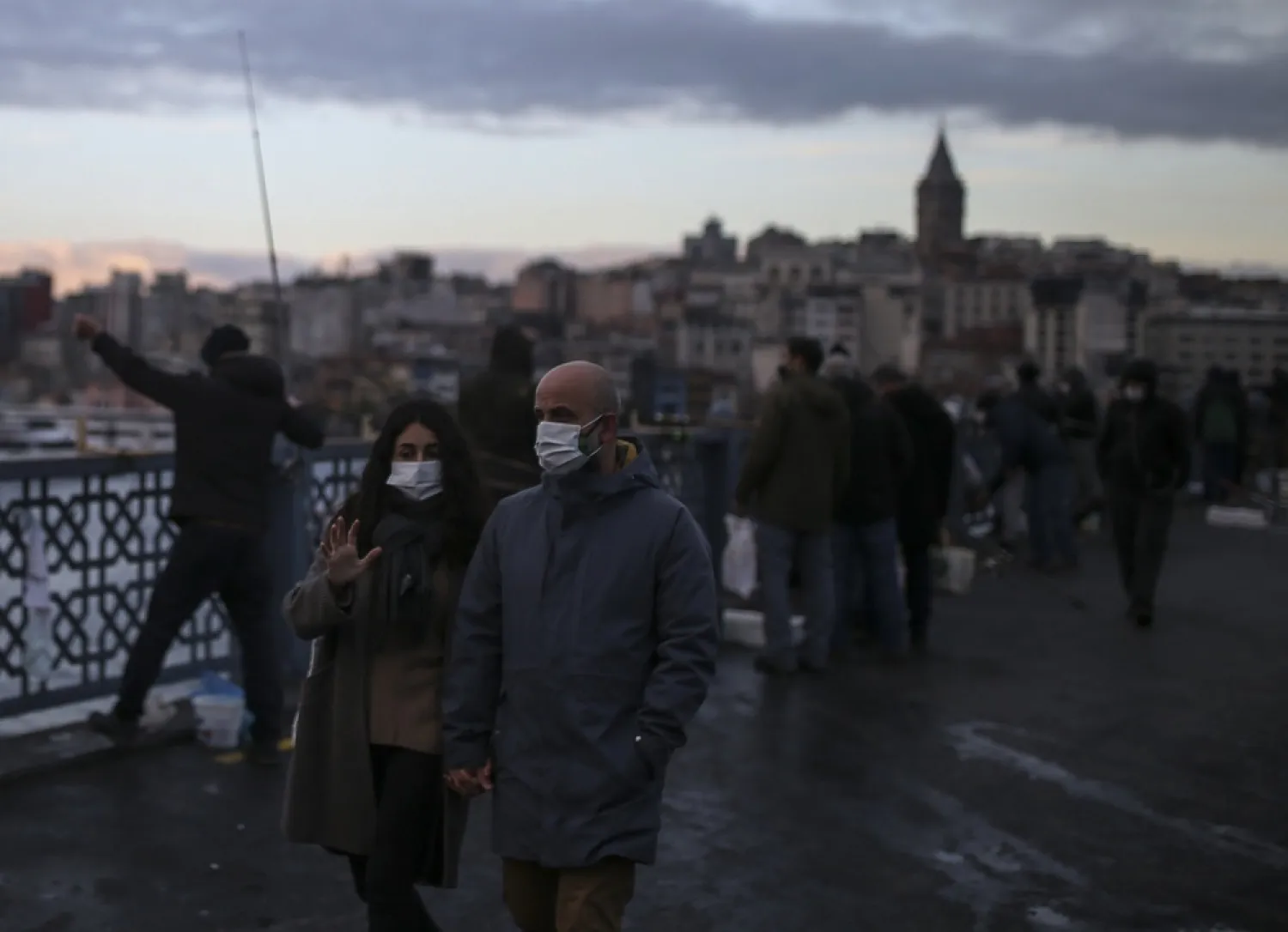 People, wearing protective masks to help curb the spread of the coronavirus, walk on the Galata Bridge over the Golden Horn in Istanbul, Dec. 21, 2020. (AP)