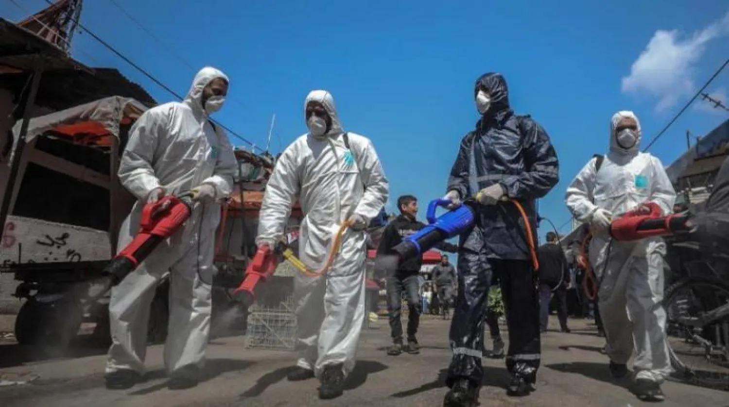 فلسطينيون يعقمون الطرق قي قطاع غزة (إ.ب.أ)