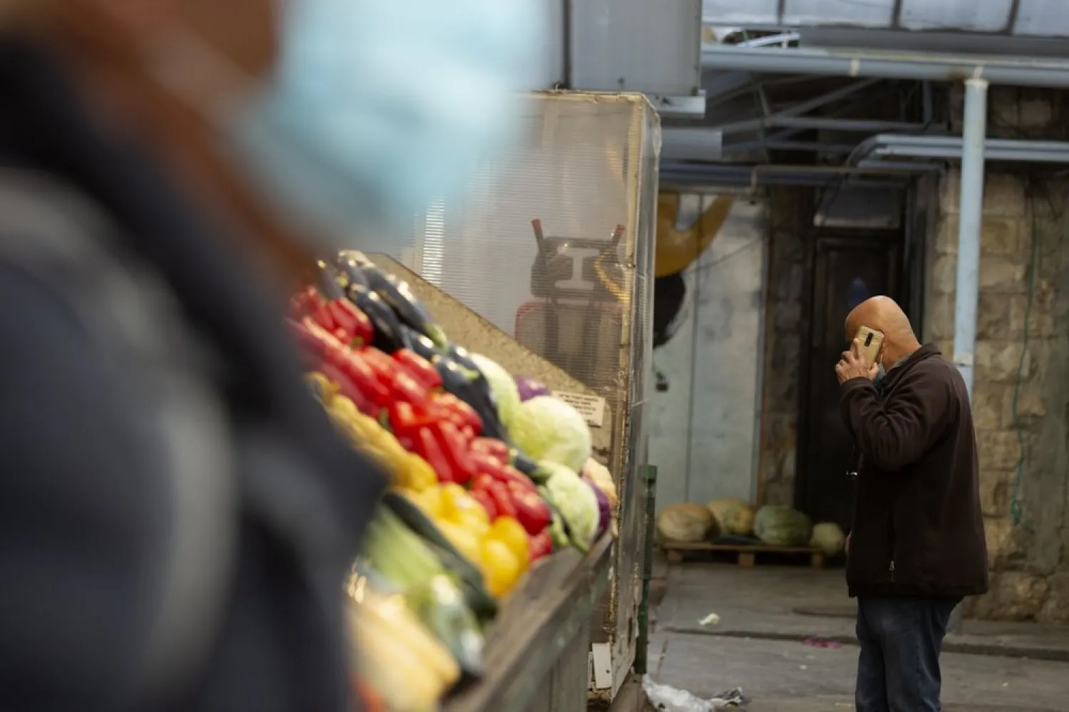 A man in a protective mask passes another man talking on his mobile phone at the Mahane Yehuda market in Jerusalem, Wednesday, Dec. 23, 2020.AP