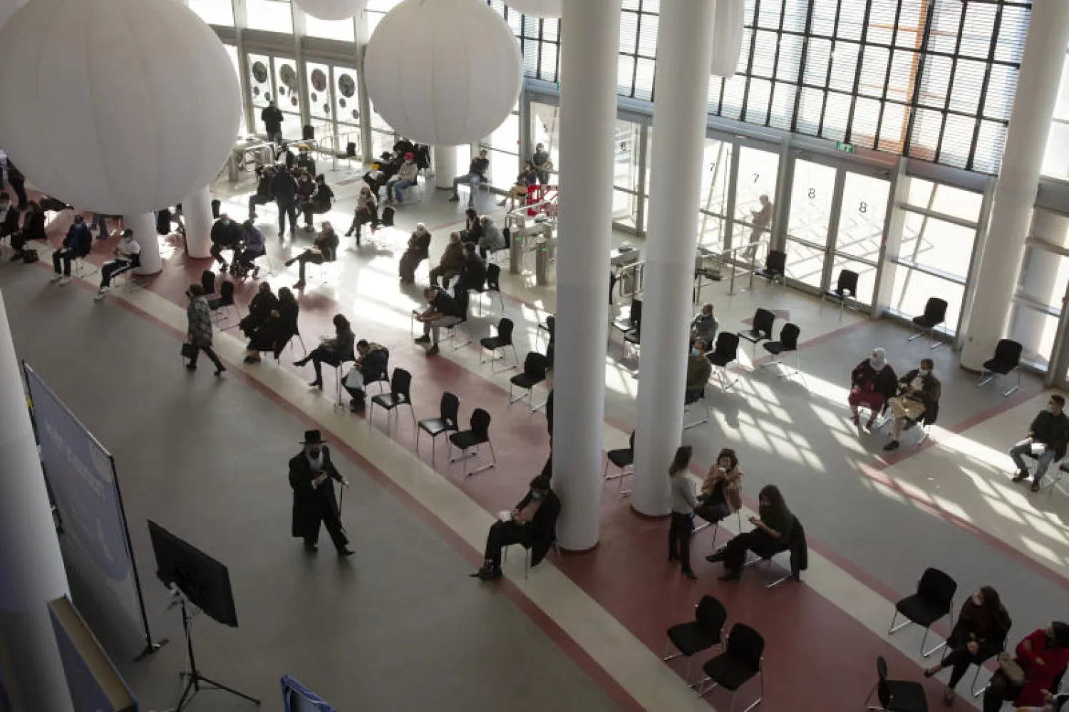 إسرائيليون ينتظرون تلقي اللقاح في أحد المراكز الرياضية بالقدس (أ.ب)