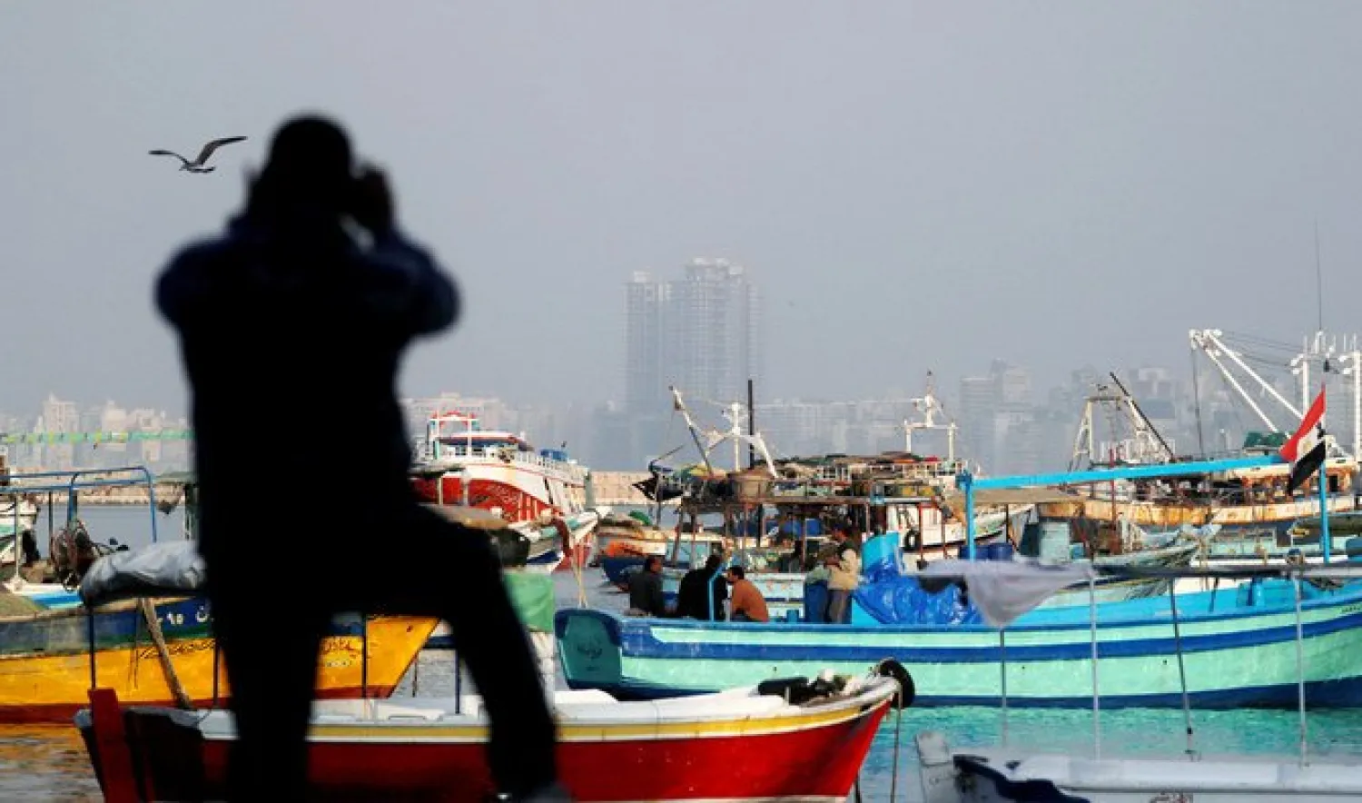 A man takes a picture of fishing boats docked along the Mediterranean Sea, north of Cairo, Egypt December 6, 2020. (REUTERS)