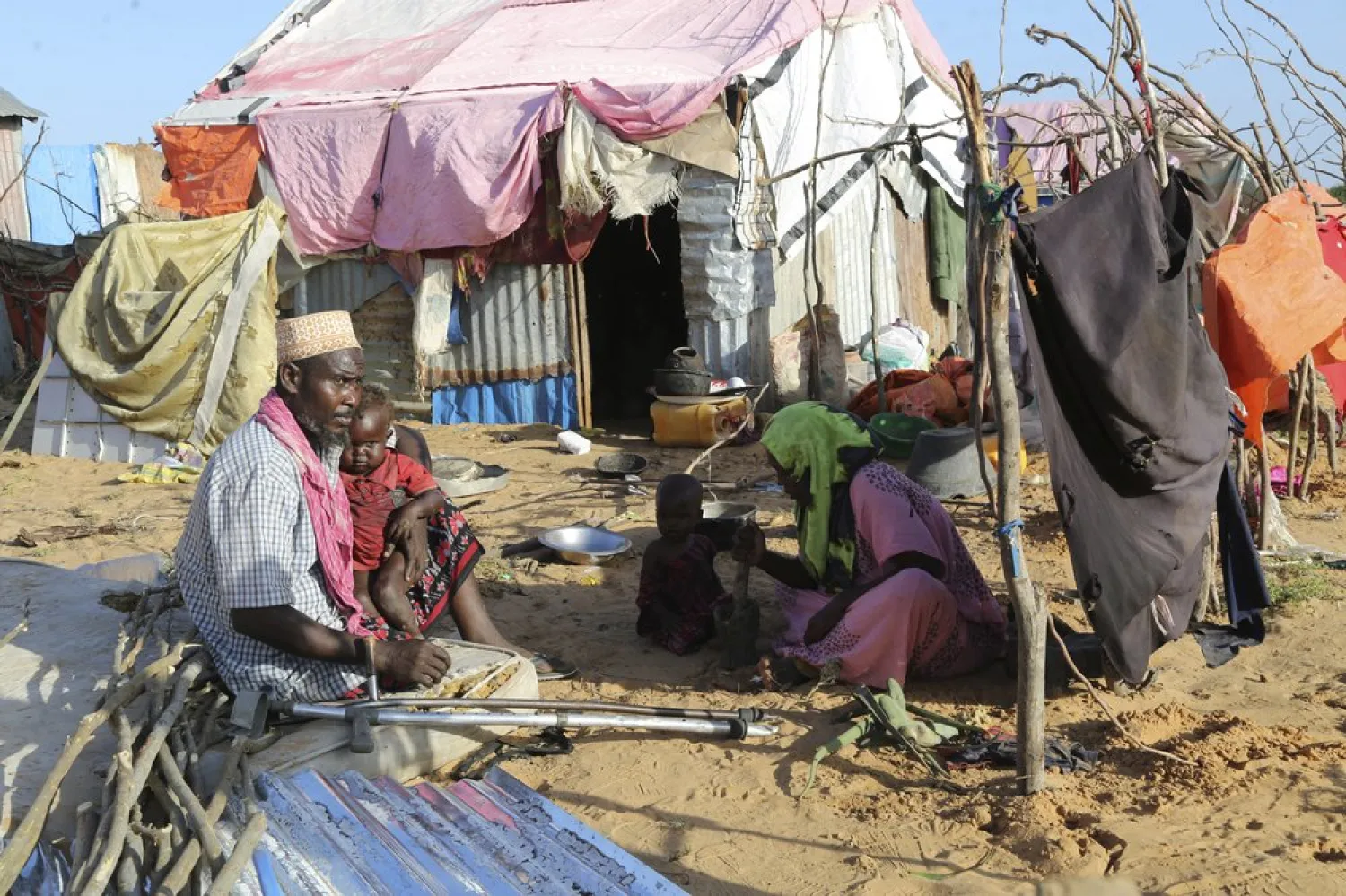 Hassan Mohamed Yusuf, 45 year old father, sits with his family at their make shift shelter at the Dayniile camp, in Mogadishu, Somalia on Thursday Dec. 17, 2020. . (AP Photo/Farah Abdi Warsameh)

