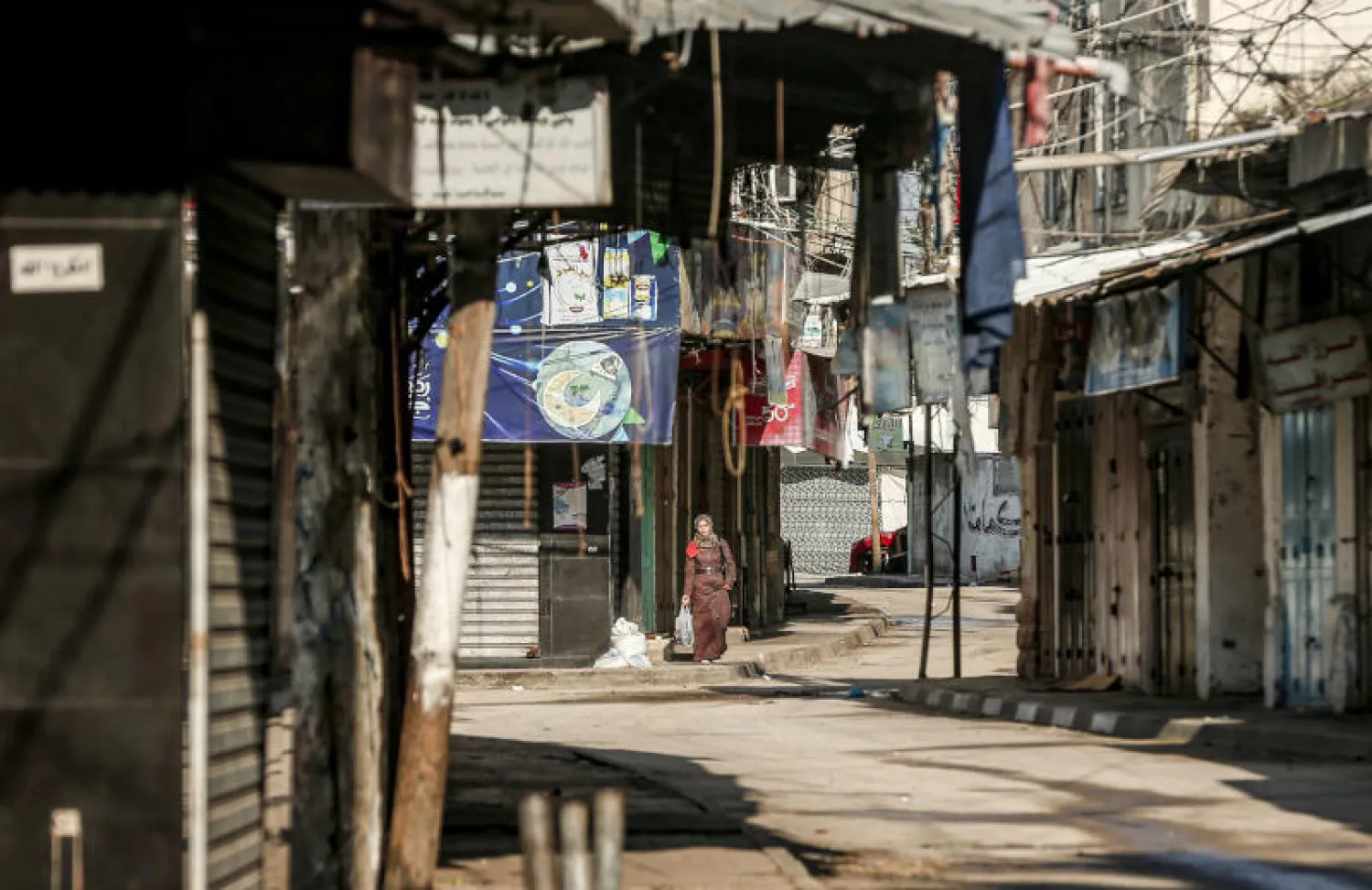 امرأة فلسطينية تمشي بالقرب من السوق الرئيسية في مدينة غزة (أ.ف.ب)