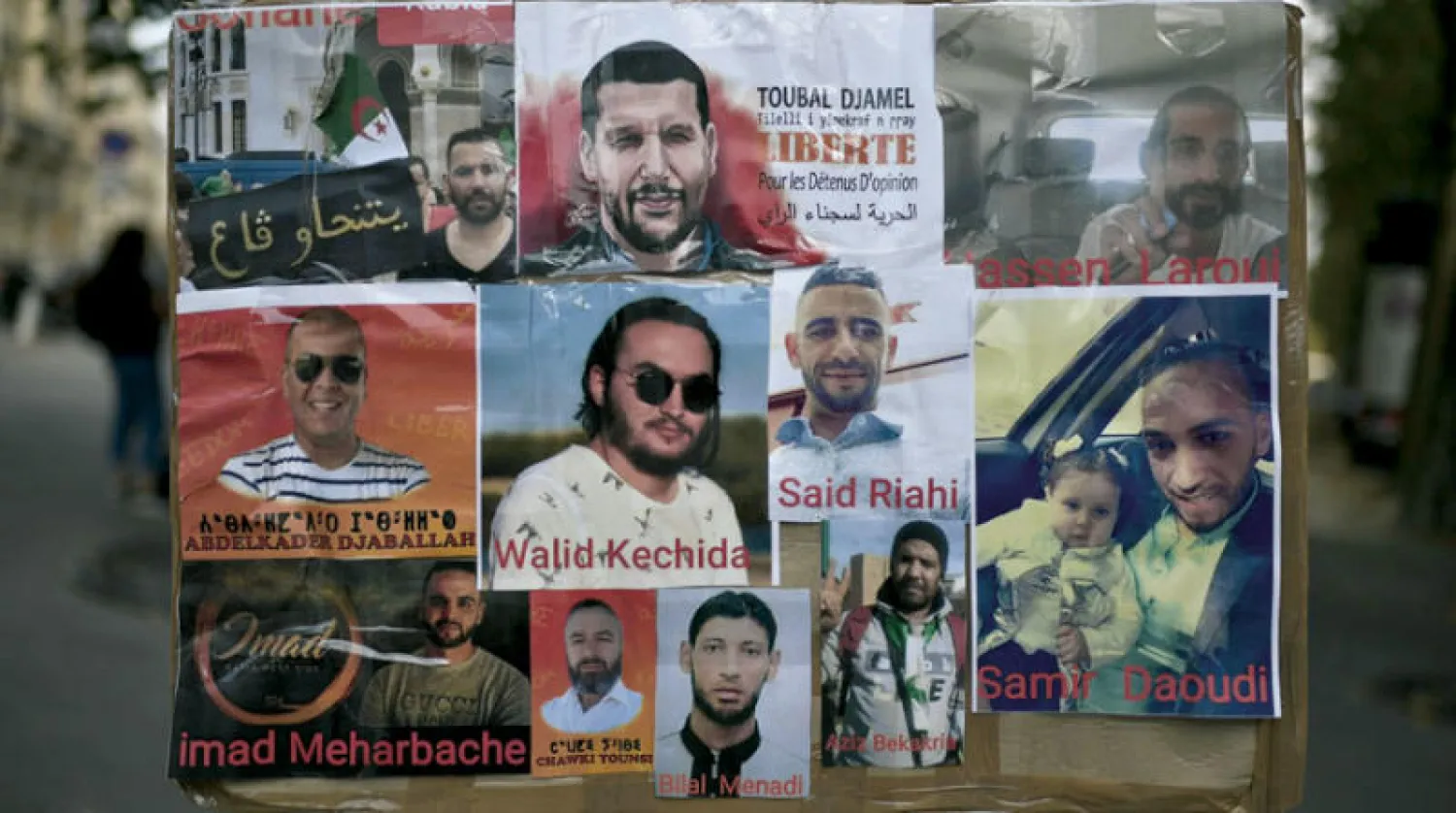 جزائريون في باريس يرفعون لافتة عليها صور حقوقيين معتقلين (أ.ف.ب)