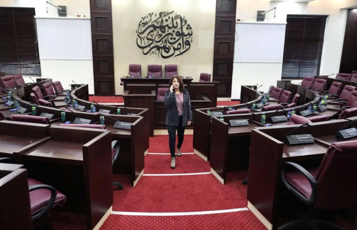  An employee inspects the main hall of the defunct Palestinian Parliament in the West Bank city of Ramallah on Dec. 7, 2019 (AFP) 

