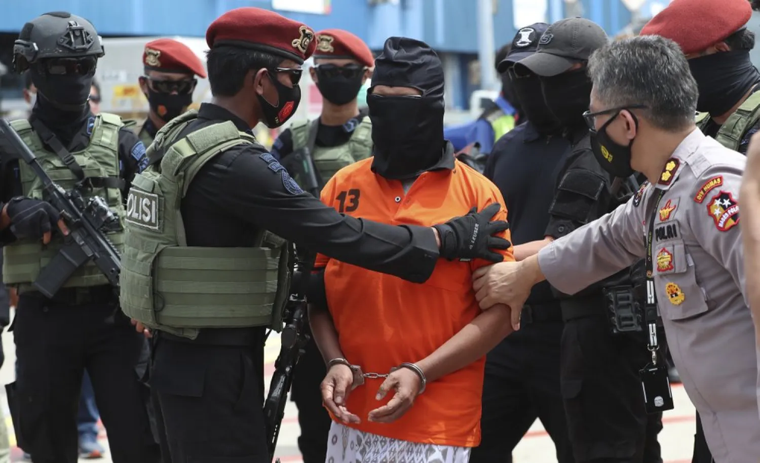 Police officers escort suspected militant, center, upon arrival at Soekarno-Hatta International Airport in Tangerang, Indonesia, Wednesday, Dec. 16, 2020. . (AP Photo/Achmad Ibrahim)
