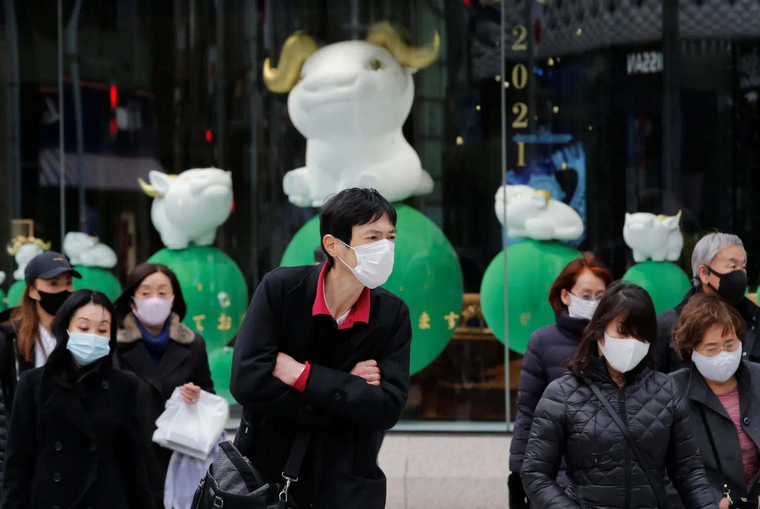 أشخاص يرتدون أقنعة واقية يمشون في طوكيو (رويترز)