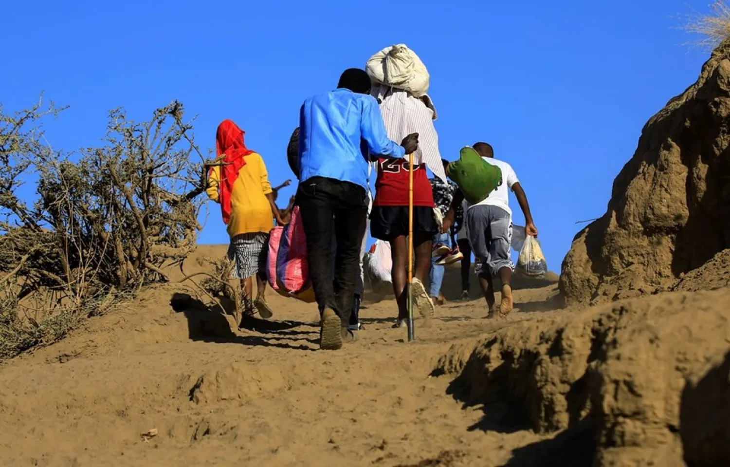Ethiopians, who fled the ongoing fighting in Tigray region, carry their belongings after crossing the Setit River on the Sudan-Ethiopia border, in the eastern Kassala state, Sudan December 16, 2020. (Reuters)