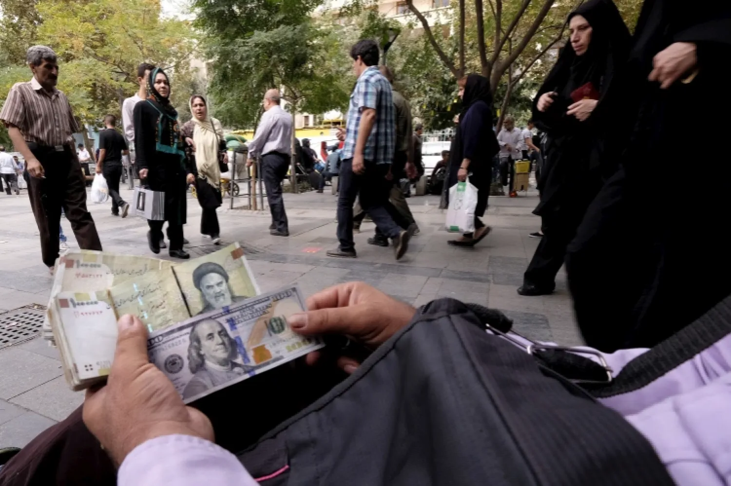 A money changer displays US and Iranian banknotes at the Grand Bazaar in central Tehran on October 7, 2015 [File: Raheb Homavandi/TIMA via Reuters]
