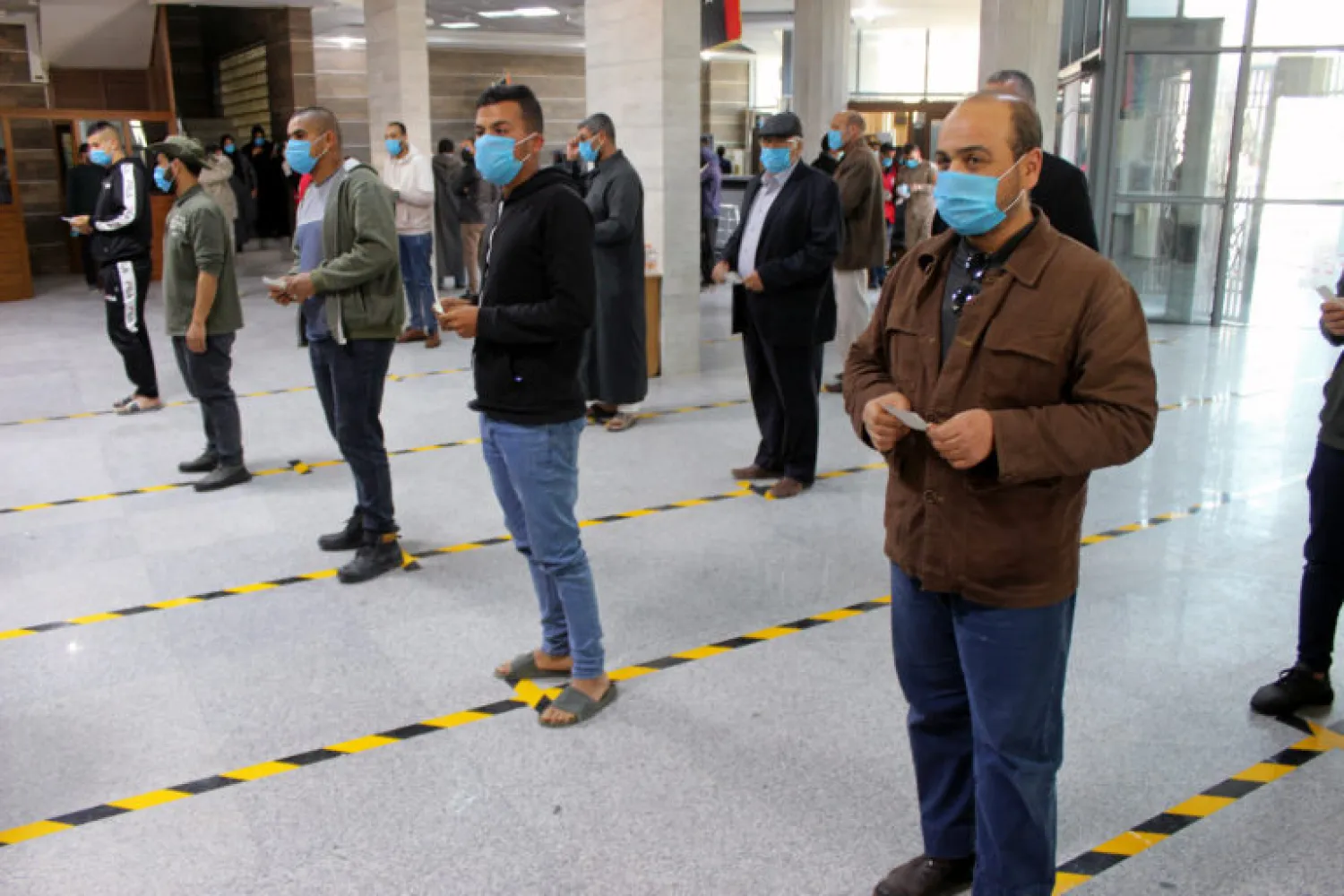 People wear protective masks and keep their distance, as part of precautionary measures against COVID-19, at a bank in Misrata, Libya, March 22, 2020. Ayman Al-Sahili/Reuters