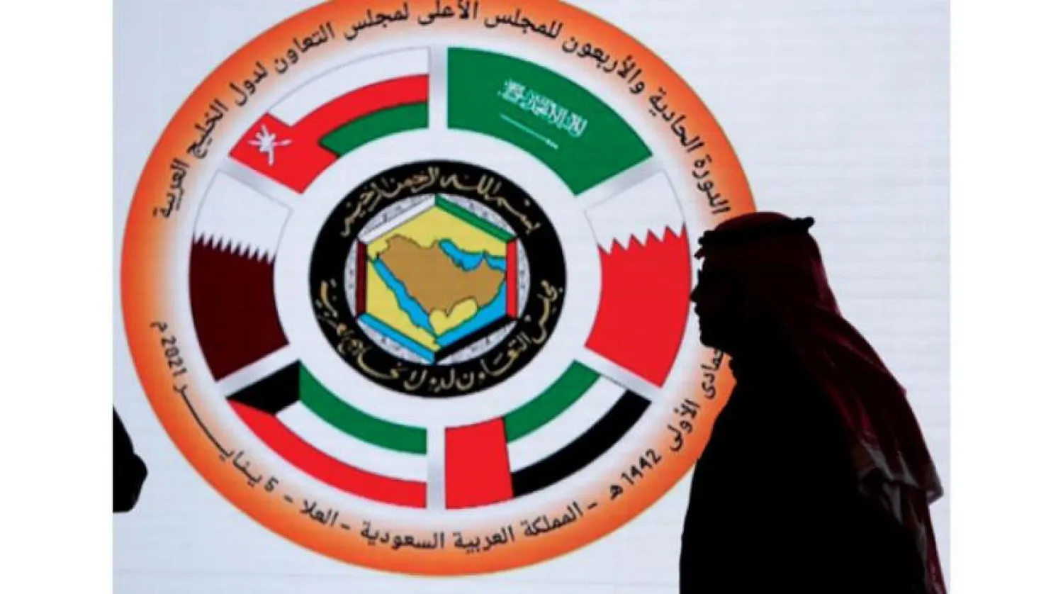 A Saudi journalist passes by a screen displaying the GCC logo. AP