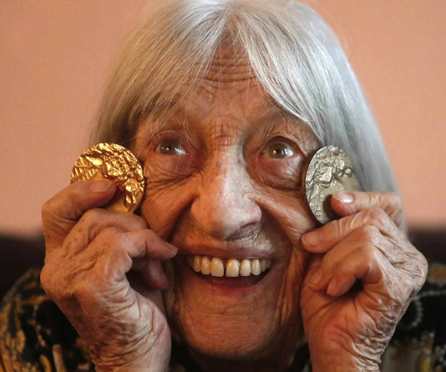 Agnes Keleti, former Olympic gold medal winning gymnast, poses for a photo with two of her Olympic medals at her apartment in Budapest, Hungary Wednesday Jan. 8, 2020. (AP Photo/Laszlo Balogh)
