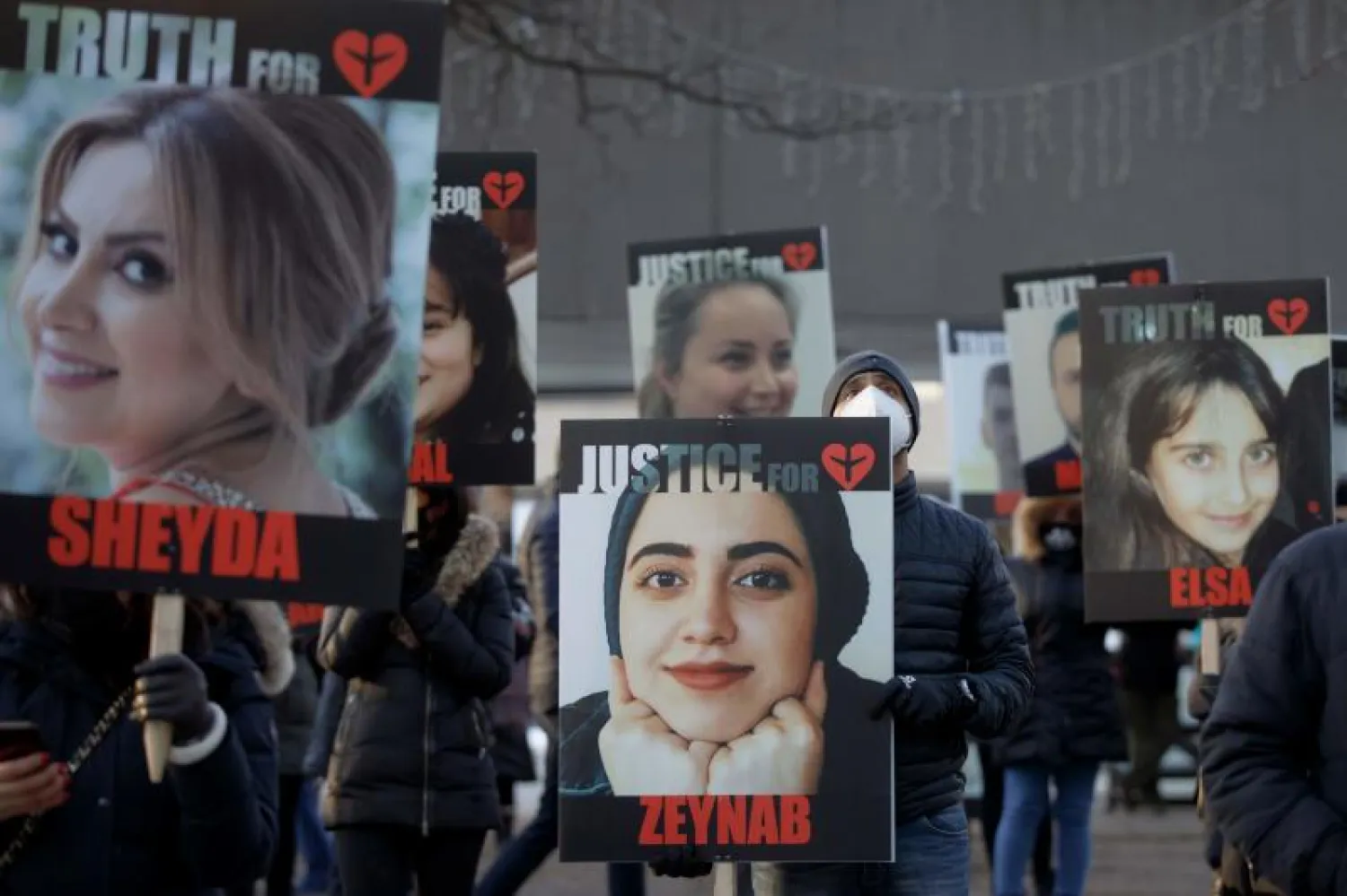 مواطنون يحملون صورا لعدد من ضحايا الطائرة الأوكرانية في تورونتو بكندا للمطالبة بتحقيق العدالة (أ.ف.ب)