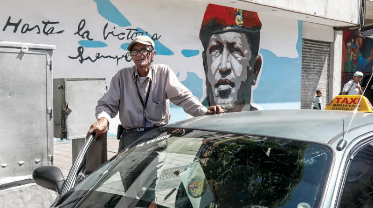 سيارة أجرة أمام لوحة للرئيس السابق هوغو تشافيز (غيتي)