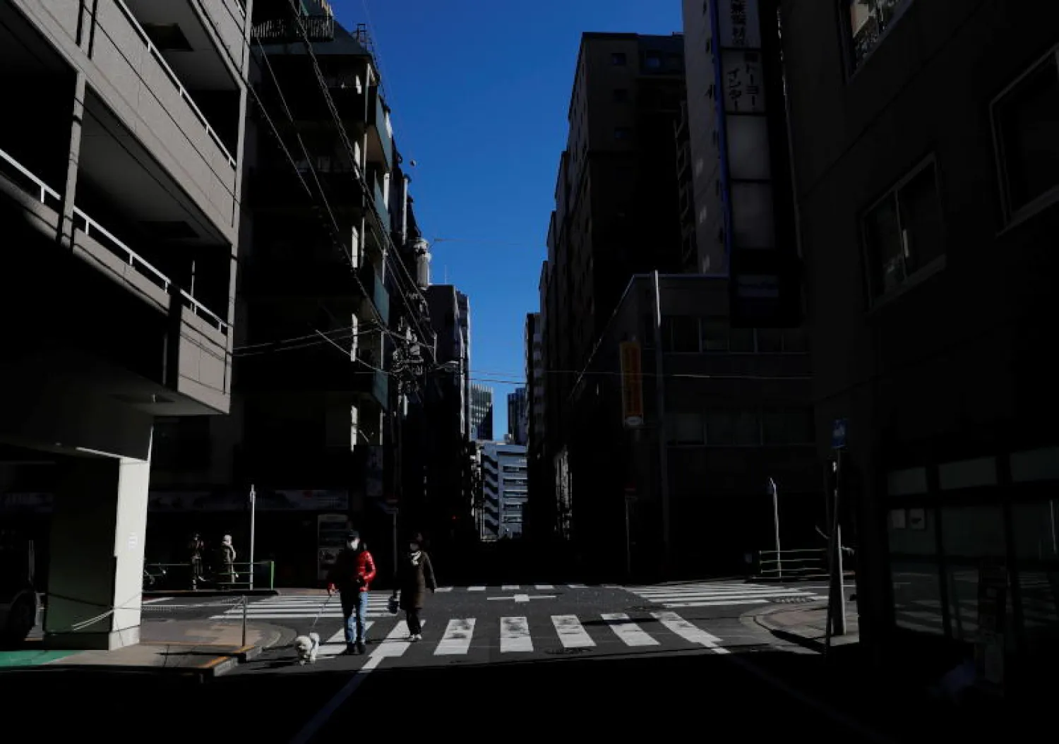 أشخاص يرتدون أقنعة واقية وسط تفشي مرض فيروس كورونا في منطقة سكنية في طوكيو (رويترز)