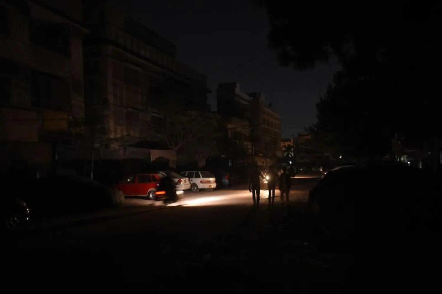 أشخاص يسيرون في منطقة سكنية خلال انقطاع التيار الكهربائي بمدينة كراتشي الساحلية الباكستانية (أ.ف.ب)